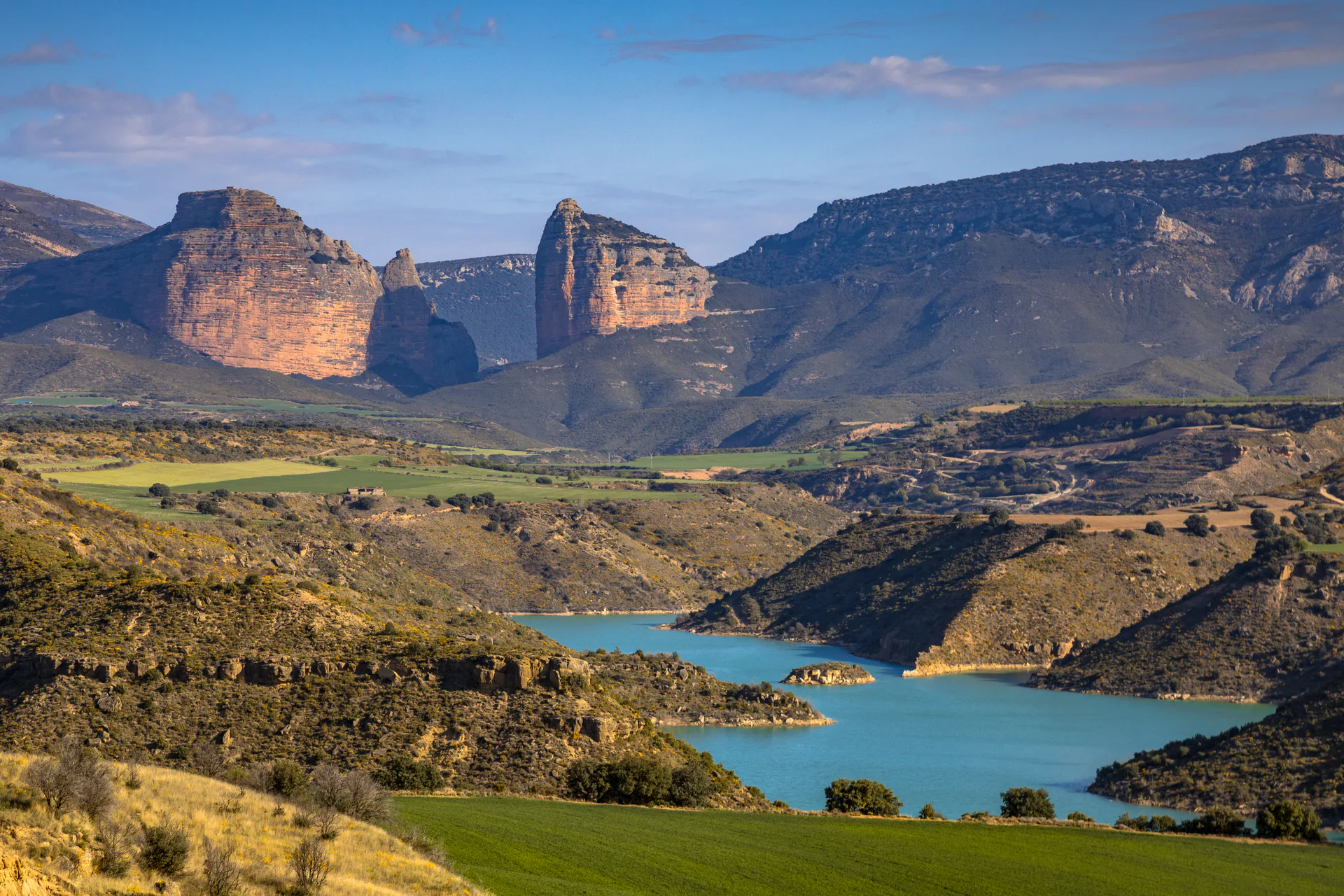 Rock towers rising above a turquoise reservoir