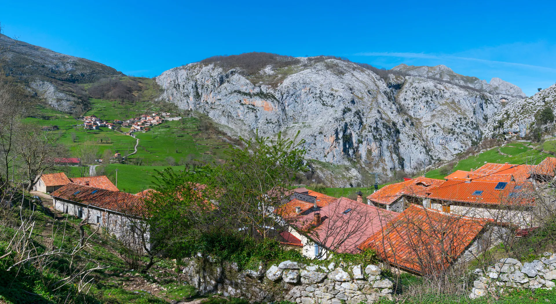 A red-roofed village beneath a limestone mountain