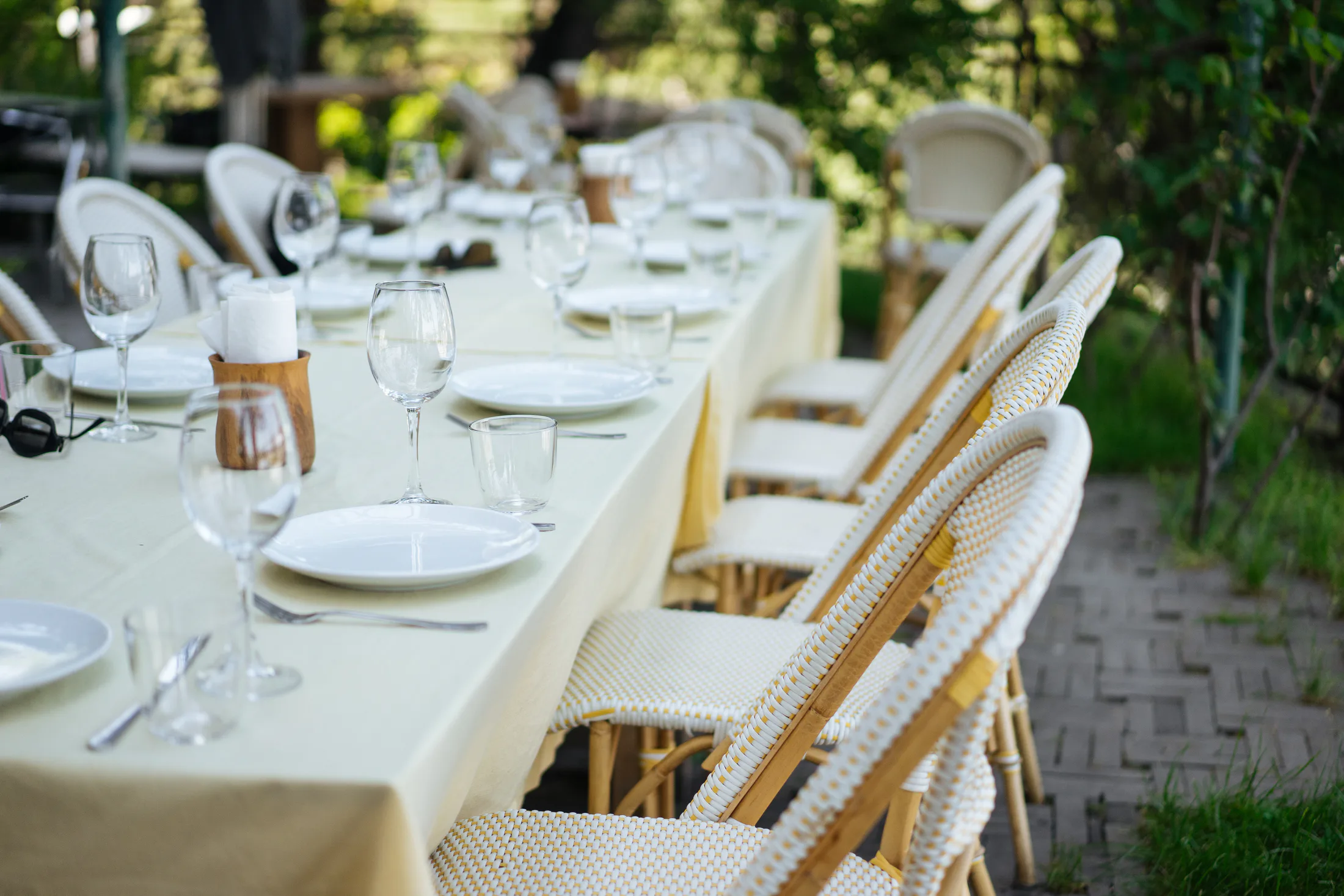 A long outdoor table set with plates and glasses.